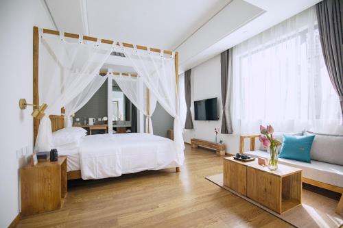 a white bedroom with a canopy bed and a couch at Dali Kong Xiang Weiwenshan Craft hotel in Dali