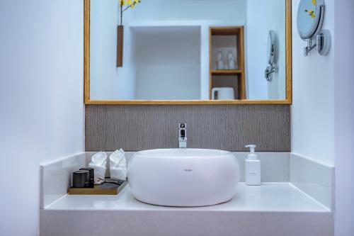 a white bathroom sink with a mirror and a bottle of soap at Dali Kong Xiang Weiwenshan Craft hotel in Dali