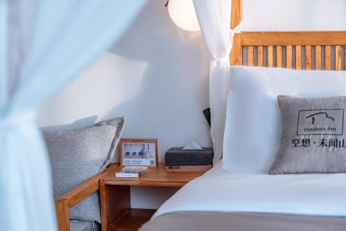 a bedroom with a bed and a table with a clock at Dali Kong Xiang Weiwenshan Craft hotel in Dali