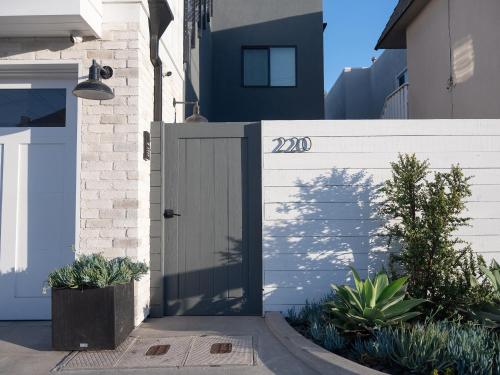 a white fence with a gate and some plants at Surf Casita - Luxury Beach Home - Steps to Ocean & Walk to everything in Newport Beach