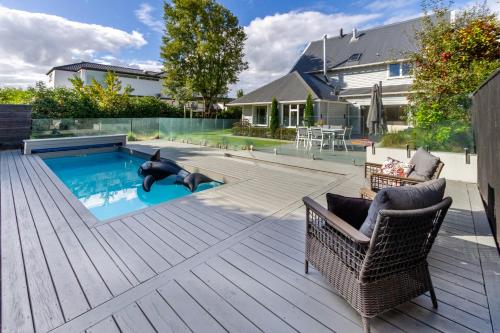 a swimming pool with a wicker chair and a wicker at Grand 5-Bedroom Villa in Fendalton in Christchurch