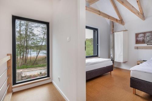 a bedroom with two beds and a large window at Holiday Home by Lake Wise ka near Baltic Beach in Wisełka