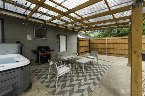 a patio with a wooden pergola and chairs and a grill at Rare Exclusive Retreat Private Hot Tub King Bed in Saskatoon