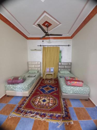 a room with two beds and a rug at Hôtel et restaurant Dyafa in Tissint