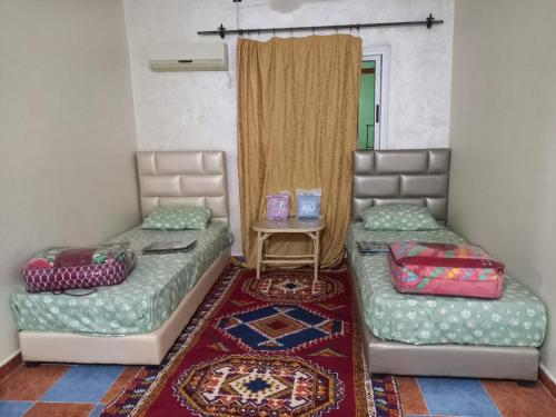two beds sitting in a room with a table at Hôtel et restaurant Dyafa in Tissint