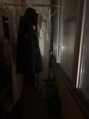 une personne dans une chambre sombre avec un manteau suspendu sur un placard dans l'établissement Carré d or, à Marseille