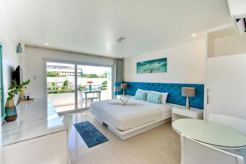 a white bedroom with a bed and a table at Indila Boracay in Boracay