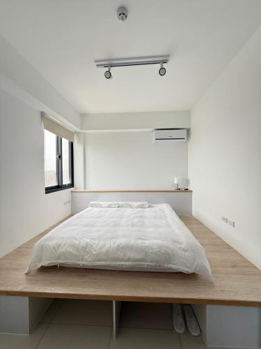 a white bedroom with a bed on a wooden platform at NewChampion冠軍民宿 寵物友善民宿1273號 in Huxi