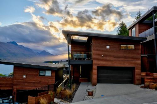 a house with a garage and mountains in the background at Stunning & modern home with fantastic lake views in Queenstown