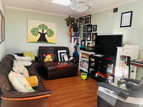 a living room with a couch and a television at Costa Mesa Homestay - Private Rooms with 2 Shared Baths and Hosts Onsite in Costa Mesa