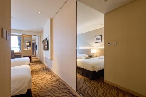 a hotel room with two beds and a mirror at Summit Hotel Seoul Dongdaemun in Seoul