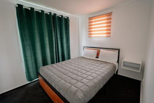 a small bedroom with a bed with a green curtain at 301 Bealey Ave Motel Very Close to City Centre and Hagley park in Christchurch