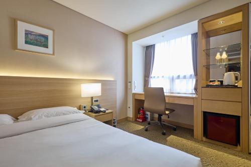 a hotel room with a bed and a desk and a window at Summit Hotel Seoul Dongdaemun in Seoul