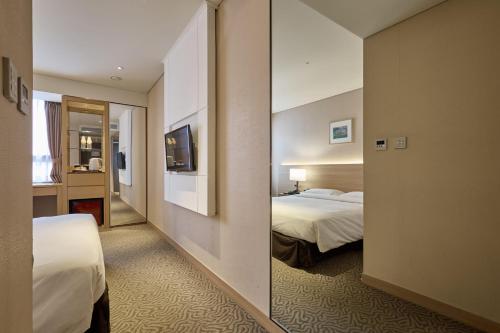 a hotel room with two beds and a mirror at Summit Hotel Seoul Dongdaemun in Seoul