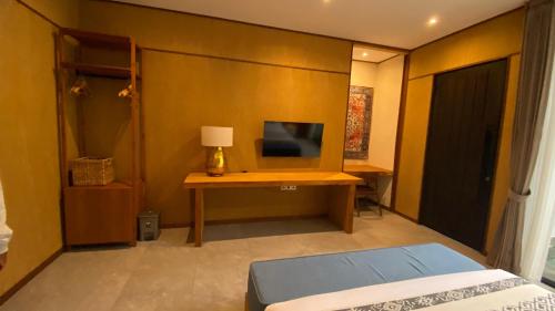 a bedroom with a bed and a desk with a television at Blue Calm Villas Bali in Tumbak Bayuh