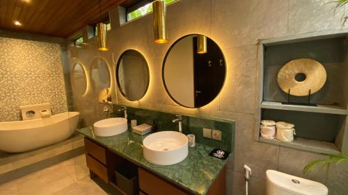 a bathroom with two sinks and two mirrors on the wall at Blue Calm Villas Bali in Tumbak Bayuh