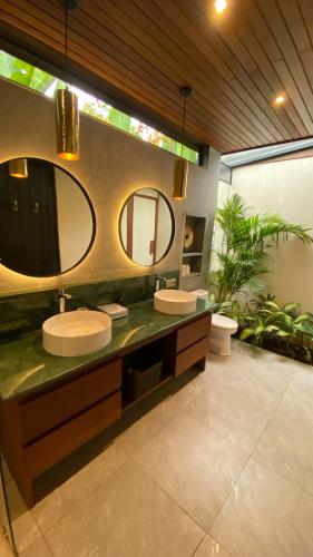 a bathroom with two sinks and two mirrors at Blue Calm Villas Bali in Tumbak Bayuh