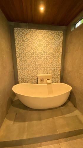 a bath tub in a bathroom with a wall at Blue Calm Villas Bali in Tumbak Bayuh