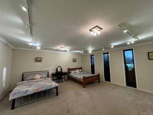 a bedroom with two beds and a table and windows at Cozy family home near suft coast 6 beds in Grovedale