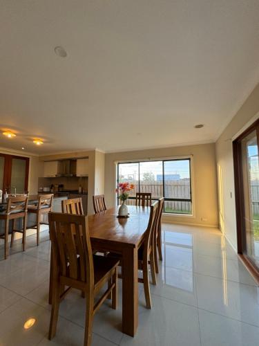 a dining room and kitchen with a wooden table and chairs at Cozy family home near suft coast 6 beds in Grovedale