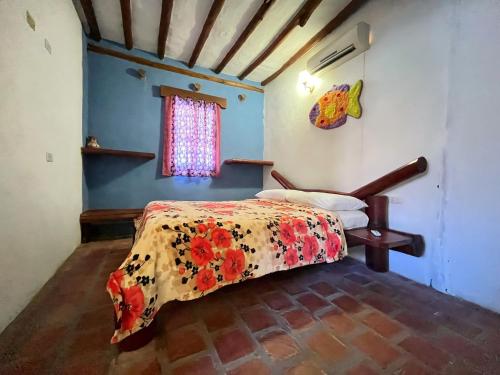 a bedroom with a bed with a floral bedspread at Posada Luisa Del Valle Guacuco in Playa Guacuco