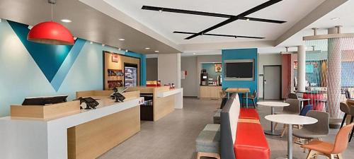 a lobby with a waiting area with tables and chairs at avid hotel Lexington - Hamburg Area by IHG in Lexington