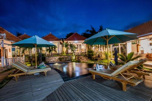 a patio with chairs and umbrellas next to a pool at Blue Sky Villa Ceningan in Nusa Lembongan