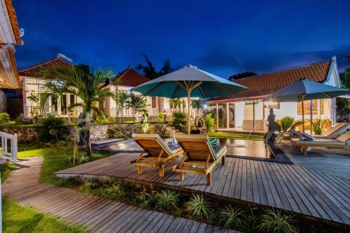 a deck with two chairs and two umbrellas at Blue Sky Villa Ceningan in Nusa Lembongan