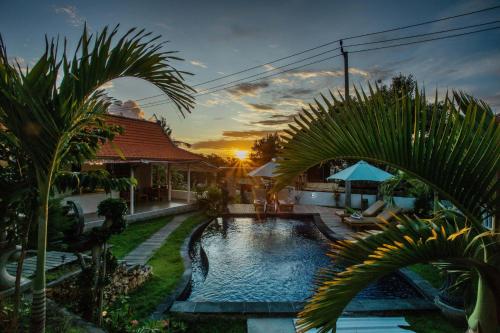 a swimming pool in a yard with palm trees at Blue Sky Villa Ceningan in Nusa Lembongan