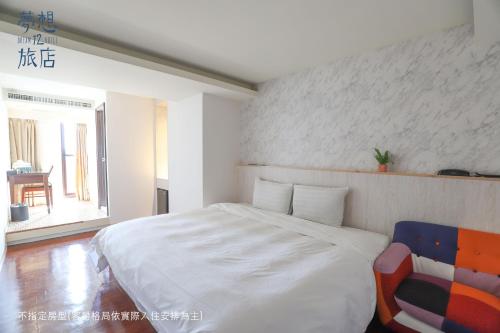 a bedroom with a large white bed and a chair at Dream 12 Hotel in Taichung