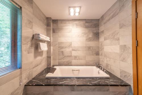a bath tub in a bathroom with marble walls at Anji Bamboo Homestay in Tangkou