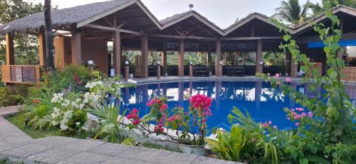 a swimming pool with flowers in front of a house at Annabel's Resort in Ferrol