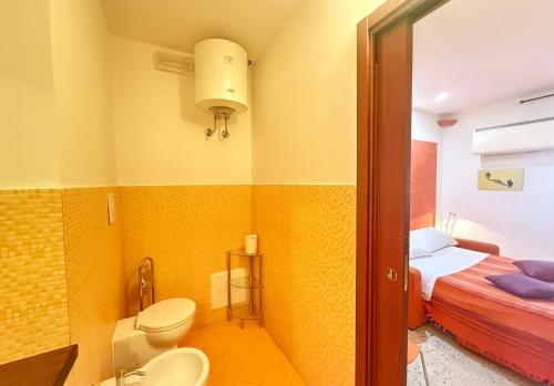 łazienka z toaletą i łóżko w pokoju w obiekcie CasinadellePalme Appartamento in centro zona porto w Trapani