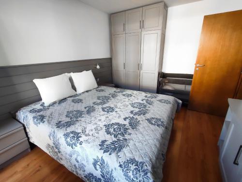 ein Schlafzimmer mit einem Bett mit einer blau-weißen Bettdecke in der Unterkunft Deluxe Apartment In Belvedere With Terrace in Bansko
