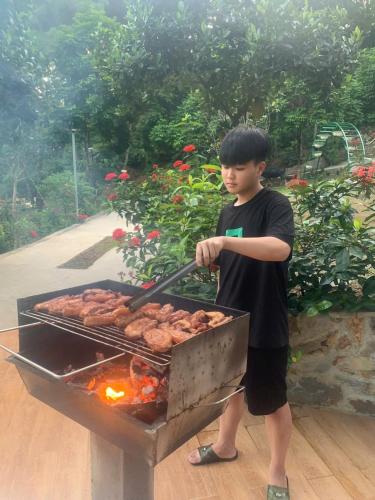 a young boy is cooking on a grill at SH Homestay - Venuestay in Sóc Sơn