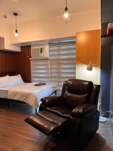 una camera con letto e poltrona in pelle di Condo in Mckinley Hill Taguig a Manila
