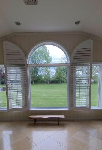 an empty room with three large windows with a bench in front at Bridle Pool House in Lansdale