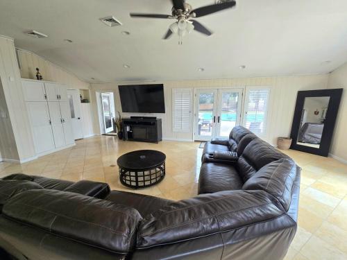 a living room with a leather couch and a ceiling fan at Bridle Pool House in Lansdale