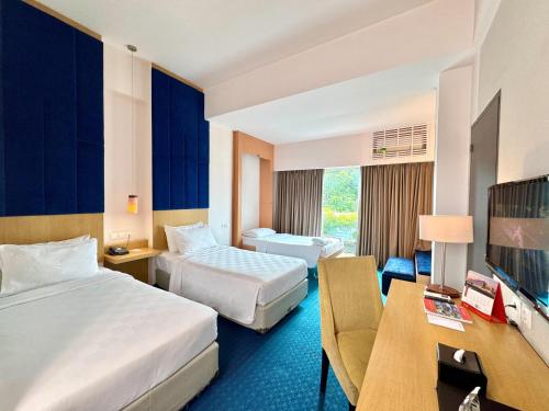a hotel room with two beds and a television at Swiss-Belinn Malang in Malang