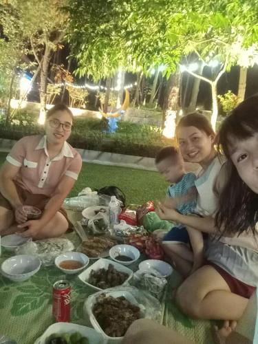 a group of people sitting around a table with food at SH Homestay - Venuestay in Sóc Sơn