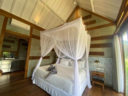 a bedroom with a white bed with a canopy at Ubud Diary Villa in Ubud
