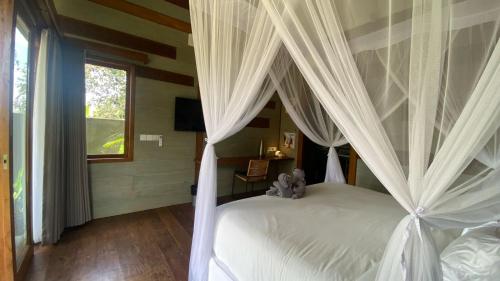 a bedroom with a canopy bed with white curtains at Ubud Diary Villa in Ubud