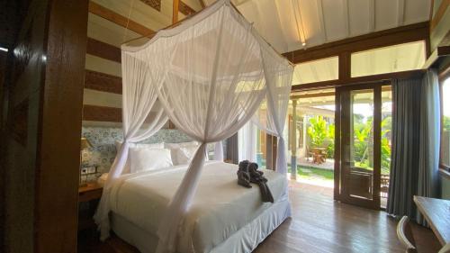 a bedroom with a white bed with a canopy at Ubud Diary Villa in Ubud