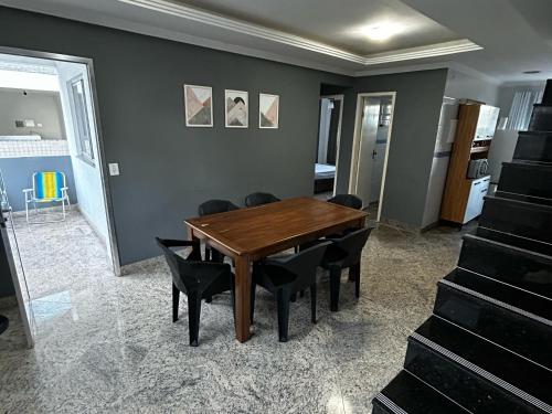 a dining room with a wooden table and black chairs at Cobertura de Frente Para o Mar e Piscina Village das Ondas in Piúma