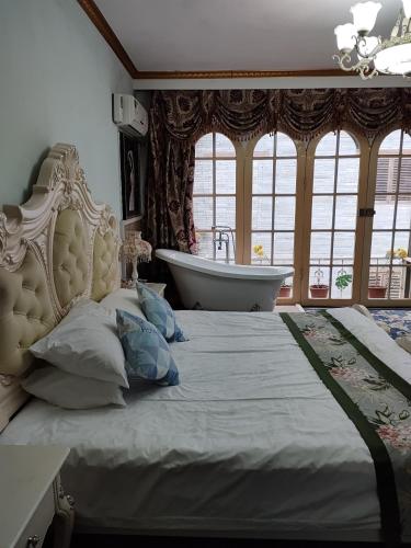 a bedroom with a bed and a bath tub and windows at Milou Inn in Yangshuo