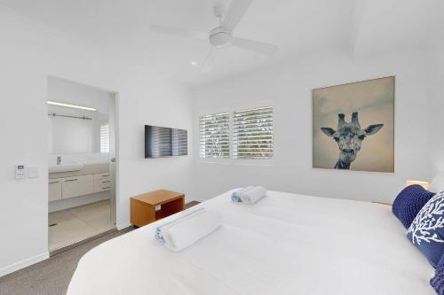 a bedroom with a large white bed with a giraffe picture on the wall at 6 The Landing in Noosaville