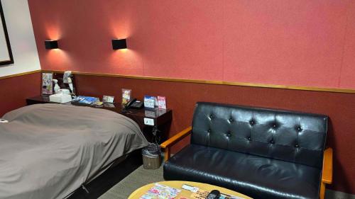 a waiting room with a leather chair and a table at ホテル ひこうせん in Yurihama