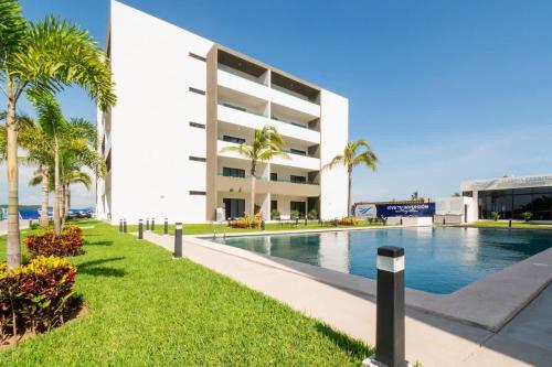 a swimming pool in front of a building with palm trees at Charming apartment 3 minutes from the beach in Mazatlán