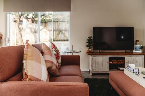 a living room with a couch and a flat screen tv at Hollyberry House in Cooma