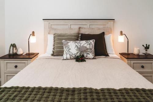 a bedroom with a large bed with pillows and two lamps at Hollyberry House in Cooma